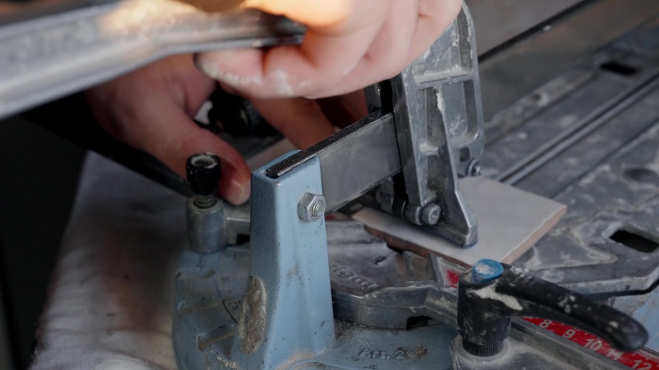 Close up of a hand operating a manual bench mounted stapling tool in a workshop
