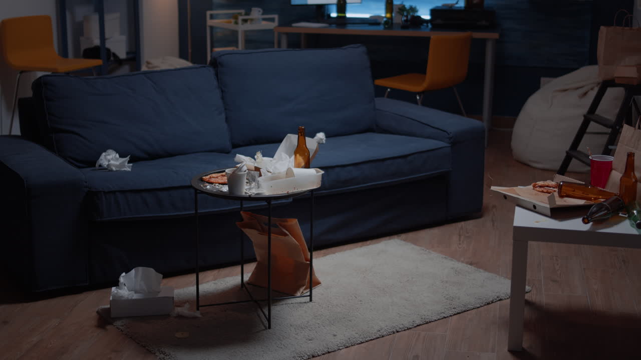 Beer bottles and pizza on table in messy living room with nobody in