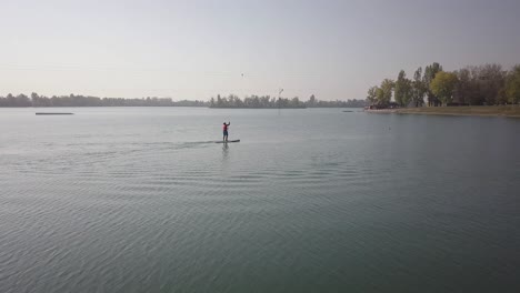 toma de drones de una persona remando en un lago en un día soleado