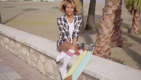 un adolescente lindo sentado en la cornisa con una patineta