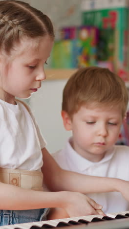girl takes little brother fingers and plays piano in children room. sister with back recovery braces teaches musical theme with toddler boy at home