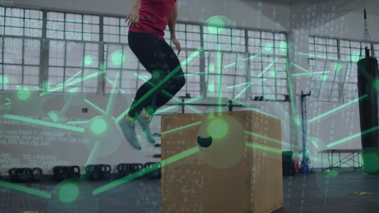 Vertical video: Squatting swinging woman jumping onto box in gym for training red top green overlay