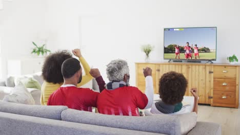 african american family watching tv with diverse male soccer players playing match on screen