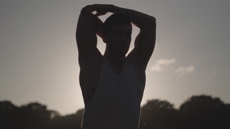 man stretches before he works out whilst being silhouetted by the evening sun in slow motion - ungraded