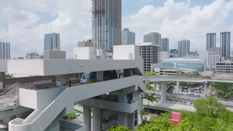 automatic system for passenger transport in city. metromover rail car leaving station elevated high above ground. miami, usa