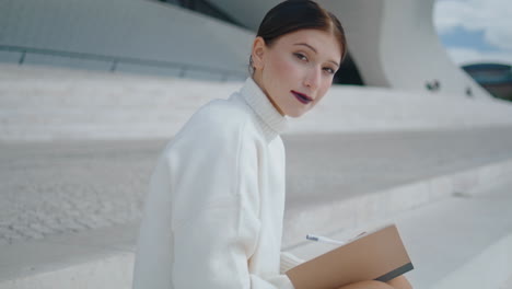 girl student making notes in notebook sitting stairs closeup. lady writing diary