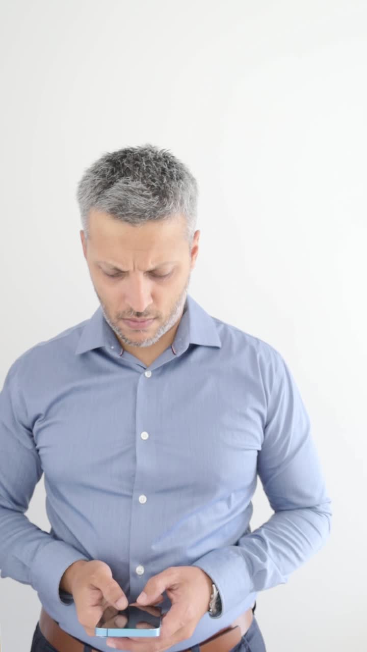 Uomo concentrato che usa lo smartphone su sfondo bianco