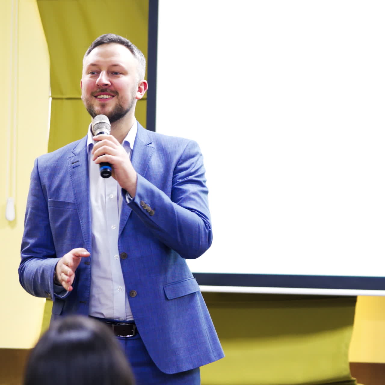 Smiling speaker male answering the questions during the conference. Meeting seminar with a professional lecturer in auditorium. Conference concept.