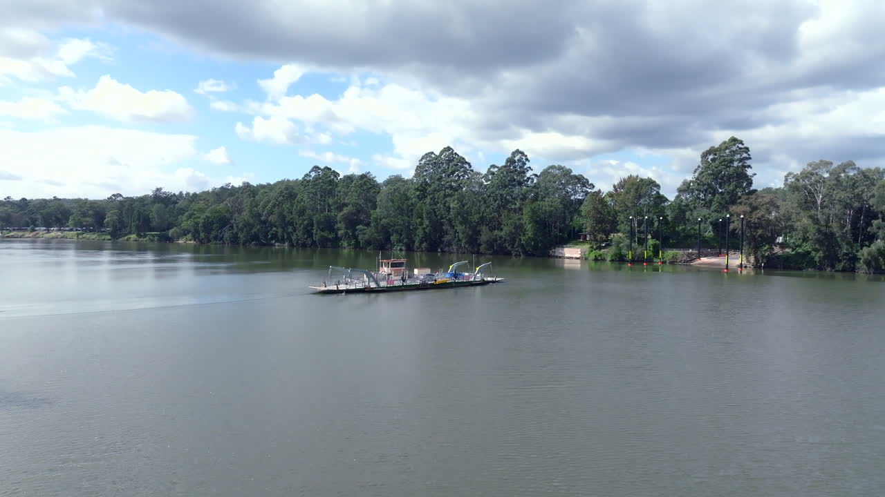 Drone shot tracking around the Sackville Ferry as it heads across the Hawkesbury river laden with cars, Australia