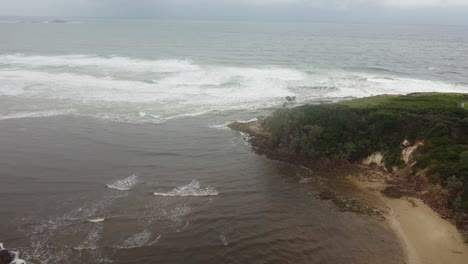 Luftaufnahme-Des-Red-Rock-Beach-In-Australien-An-Einem-Bewölkten-Tag,-Der-Auf-Eine-Halbinsel-Zufliegt