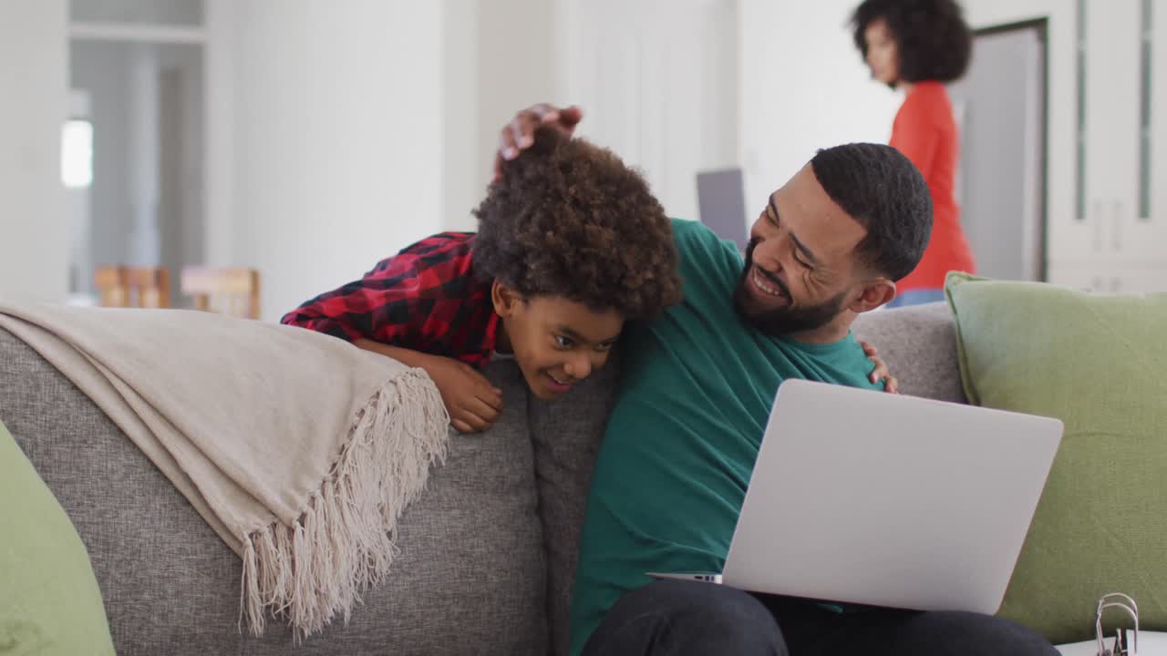 Father embracing his son while using laptop at home