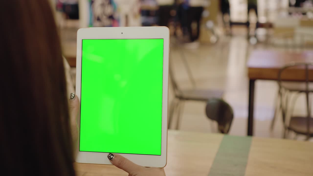 Mano di donna che tiene un tablet con display a schermo verde vuoto per chroma key, mentre legge le notizie