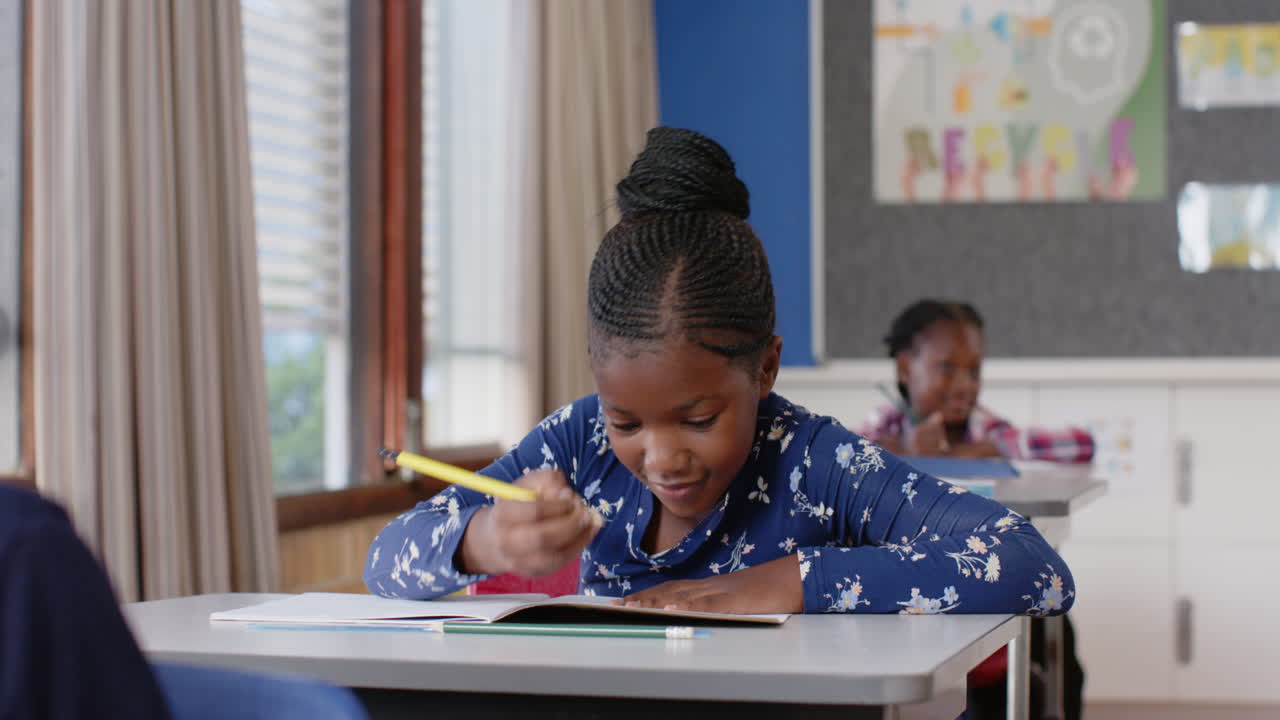 In school, girl writing in notebook at desk, concentrating on her work