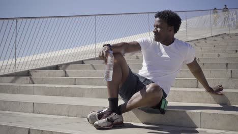 Lächelnder-Afroamerikanischer-Mann,-Der-Nach-Dem-Training-Wasser-Trinkt.