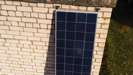 Panel-Solar-Que-Alimenta-Un-Edificio-De-Garaje-De-Ladrillo-Blanco,-Elevación-Aérea