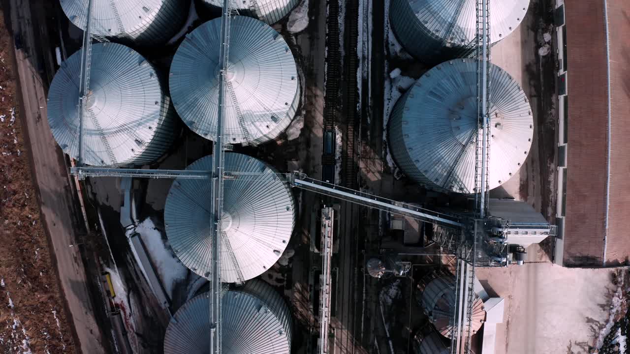 위에서 볼 수 있는 금속 실로: 곡물을 저장하고 가공하기 위한 대형 컨테이너, 농장 내의 은색 곡물 엘리베이터, 위에서 보이는 저장 크, 곡물이 있는 실로.