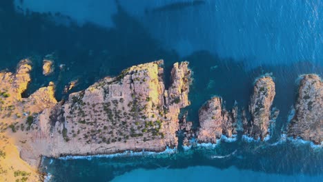 aerial view of rugged rocky cliffs overlooking the deep blue sea in haweria, tunisia, with a small structure nestled among the formations.