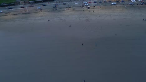 Toma-Aérea-De-Una-Playa-Al-Lado-De-Una-Carretera-Muy-Transitada-En-Scarborough-North-Yorkshire-Durante-La-Puesta-De-Sol-En-Inglaterra