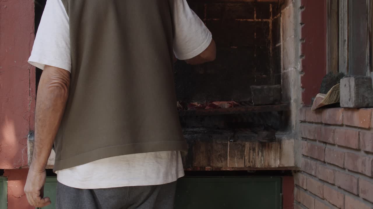 4K at 60fps (slow motion) - Man cooking a barbecue on a rusty grill on a sunny day - BBQ (asado) - Relax and warm mood