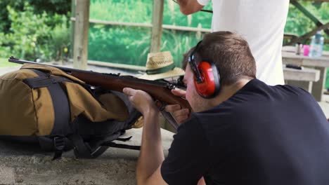 young man firing a shotgun at an outdoor shooting ground