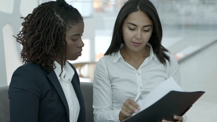 Young businesswomen signing papers