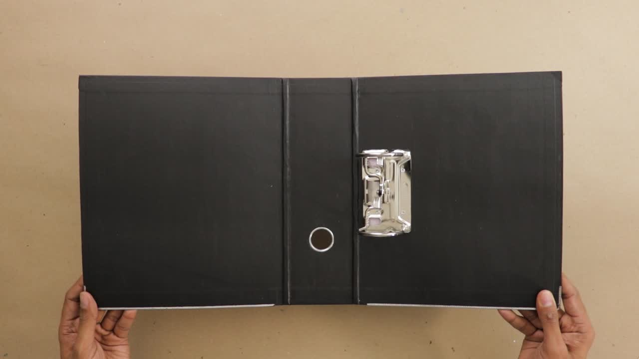 Holding open black lever arch file with ring binder on office desk