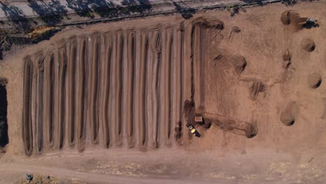 Aerial-of-yellow-tractor-spreading-compost-mixture-on-a-farm