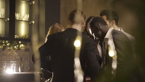 group friends wearing stylish clothes while talking and holding champagne glasses at new year's party