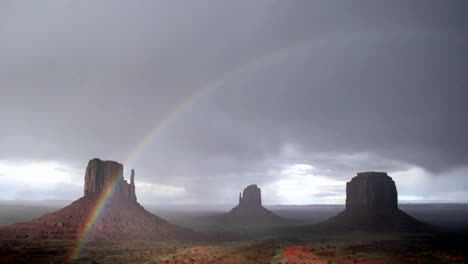 un arco iris se forma a la luz del sol después de una tormenta en monument valley, utah