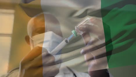 Animation-of-flag-of-ivory-coast-waving-over-doctor-wearing-face-mask-and-holding-vaccine