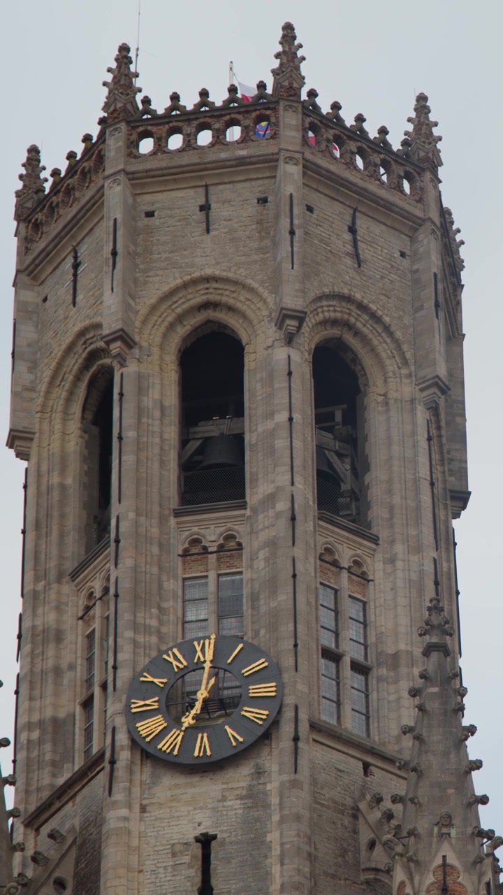 Camera tilts upward revealing historic bell tower clock against overcast sky, soft natural daylight