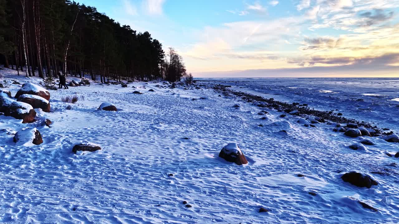 Costa congelada do Mar Báltico com neve, gelo e pegadas, mostrando o inverno frio em vista aérea em uma noite fria.