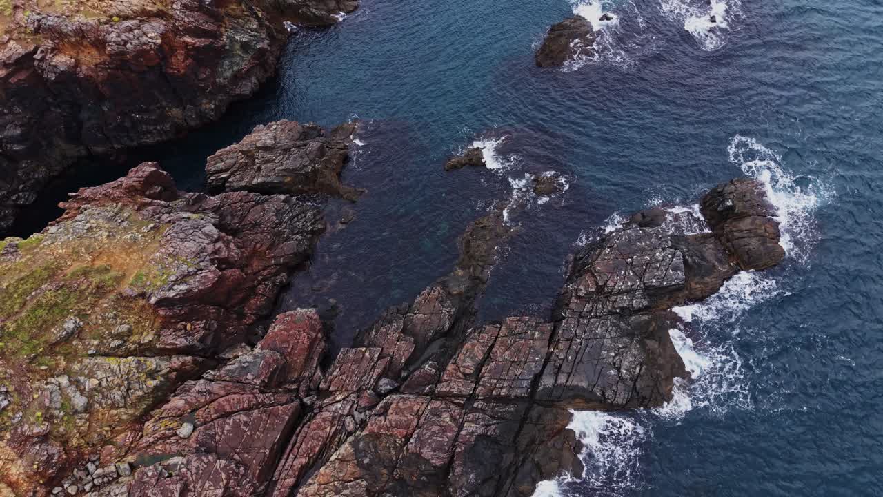 Costa rocciosa con onde che si infrangono sugli scogli vicino alla riva dell'oceano