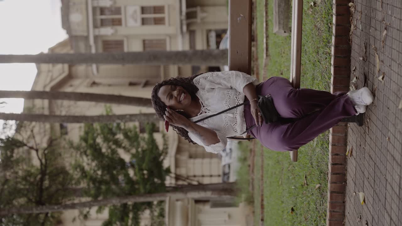 A woman smiles while sitting on a park bench