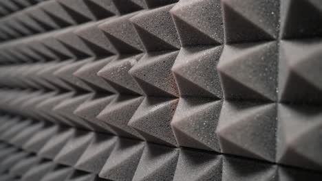 primer plano de paneles de espuma acústica con forma de pirámide, diseñados para absorber ondas sonoras, reducir el eco y controlar las reflexiones sonoras en un entorno de estudio