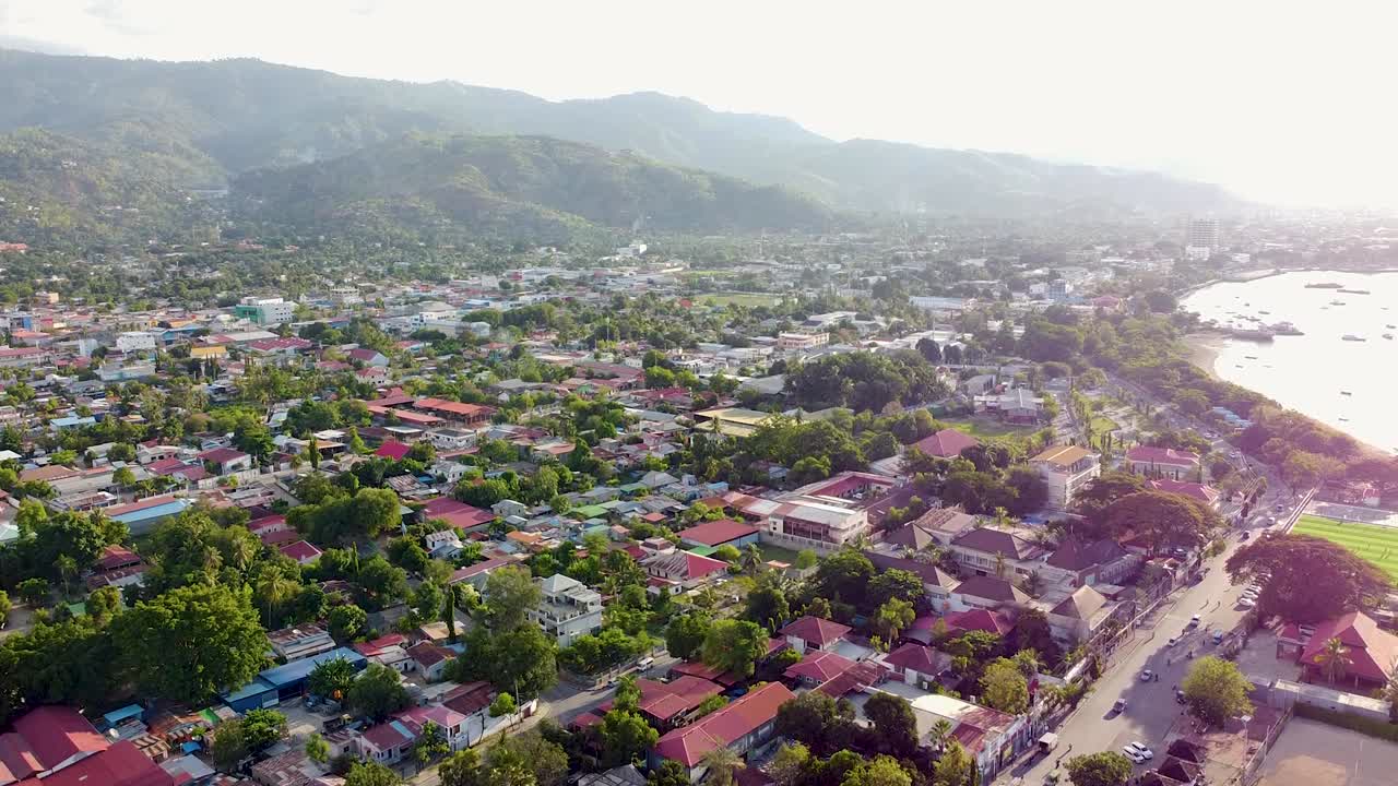 Scenic aerial view overlooking the capital city Dili, Timor-Leste in Southeast Asia with houses, shops, and buildings, green trees, and traffic