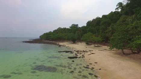 Toma-Aérea-De-Una-Playa-Con-Un-Pequeño-Muelle-De-Madera-En-Una-Isla-Tropical-Tailandesa-Con-Selva-Y-Océano-Claro-En-Koh-Kood,-Tailandia