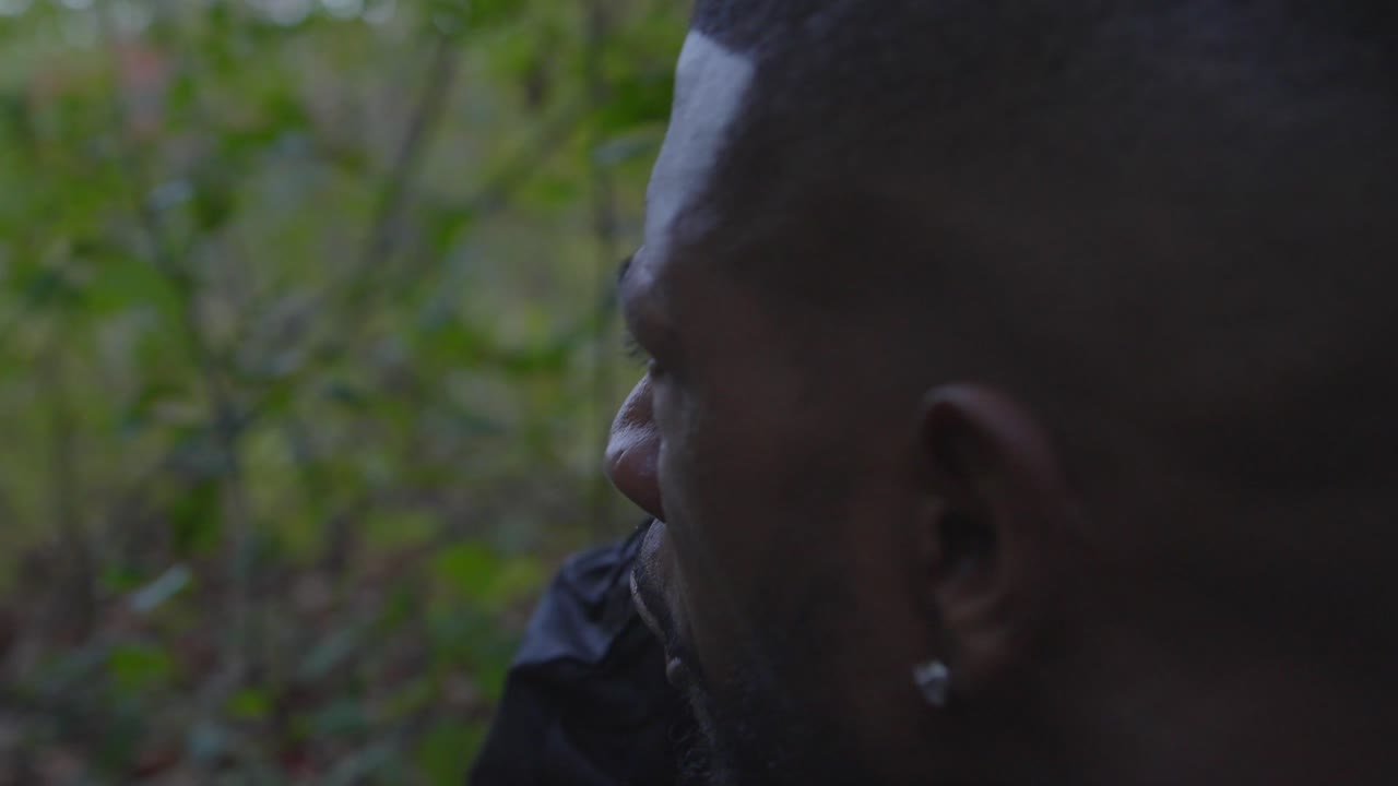 hombre negro gritando órdenes por teléfono desde un área boscosa remota