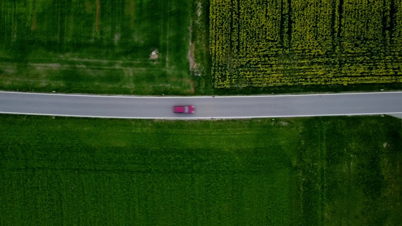 빨간색 자동차가 시골의 작은 집을 지나가고 있습니다.