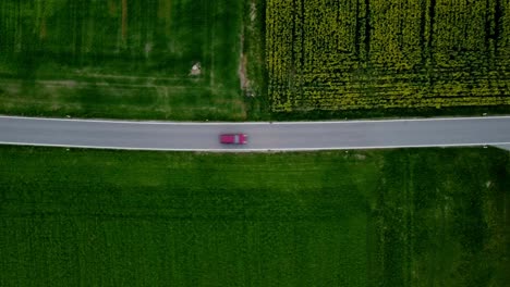 red cars is passing by a small house in the country side