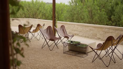 outdoor seating area with leather butterfly chairs on a cobblestone patio