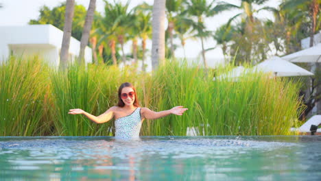 happy pretty exotic female in swimsuit playing in swimming pool, spraying water, full frame slow motion