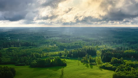 time lapse sun rays between moving clouds skyline, shadow over green forest landscape