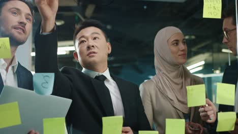 close up view of multiethnic business people group working in a modern office while writing on glass in a cabinet with sticky notes 5