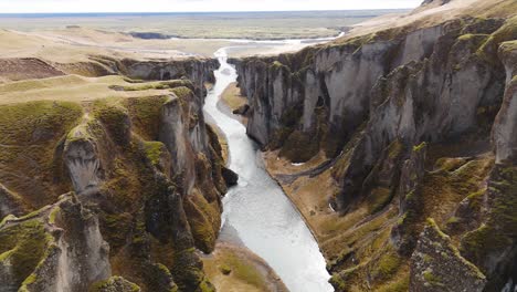 Paisaje-Del-Cañón-Fjadrargljufur-Con-Un-Río-Que-Fluye-Entre-Acantilados