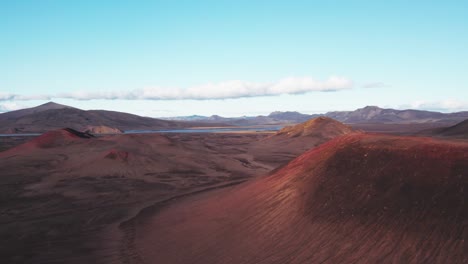 aerial: flyover reveal view of dormant and vibrant red and black volcano on a clear day in iceland highlands