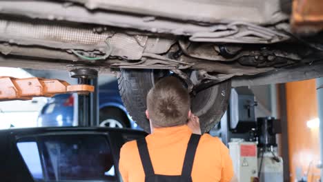 mechanics working on a lifted car in an auto repair shop