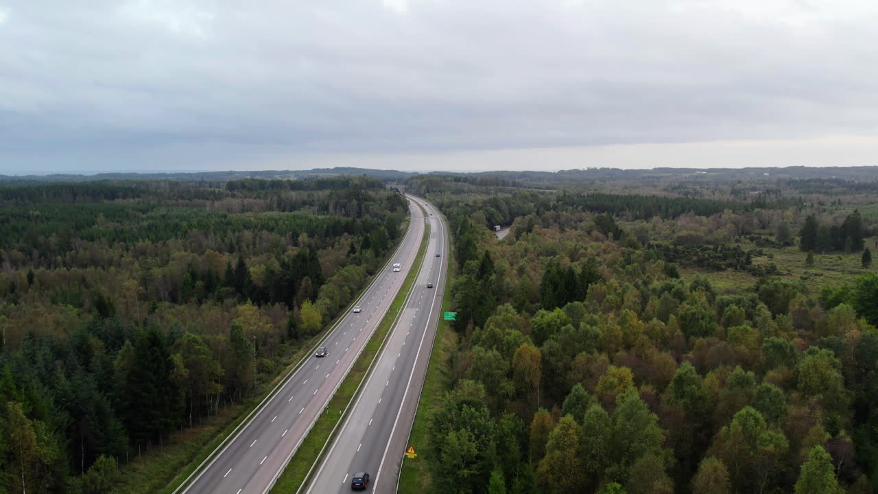 Letecké záběry z dronu dálnice E6 protínající les a venkovskou krajinu v jižním Švédsku. Kontrast mezi dopravním koridorem a přírodní krajinou přes hřeben Hallandsåsen.