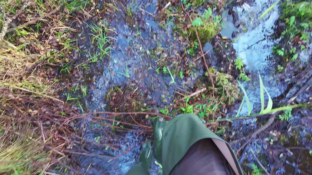 hombre con altas botas de goma caminando en un paisaje pantanoso, pov vista en cámara lenta