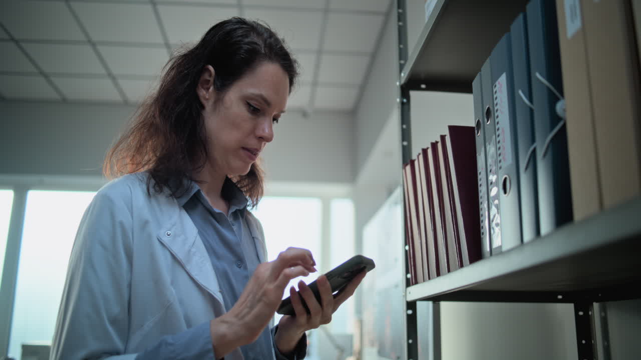 médico usando un teléfono inteligente en una biblioteca